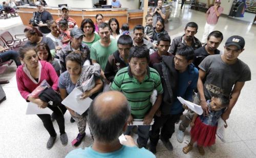 Immigrants listen to instructions from a volunteer inside the bus station after they were processed and released by U.S. Customs and Border Protection.