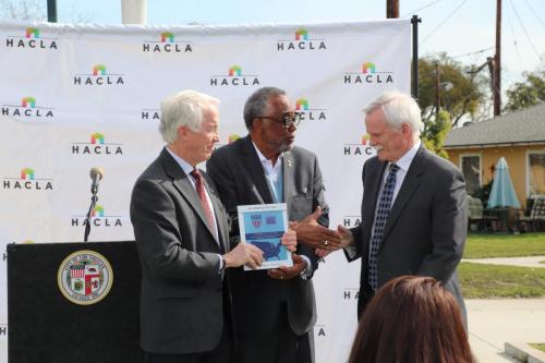 The League's President, Doug Linkhart, presents the 2022 AAC Award plaque to Doug Guthrie, President and CEO, Housing Authority of the City of Los Angeles and Councilman Curren D. Price during a community celebration. 