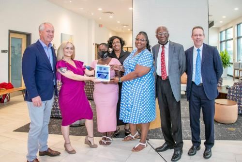 The Louisville team and League board member, Tony Peyton, pose with their 2022 AAC Award plaque during a community celebration. 